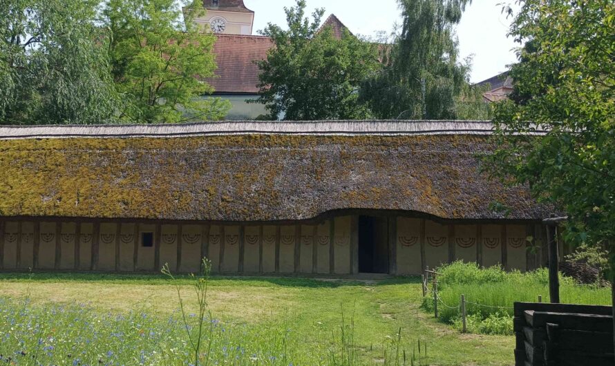 Kirche hinter jungsteinzeitlichem Haus